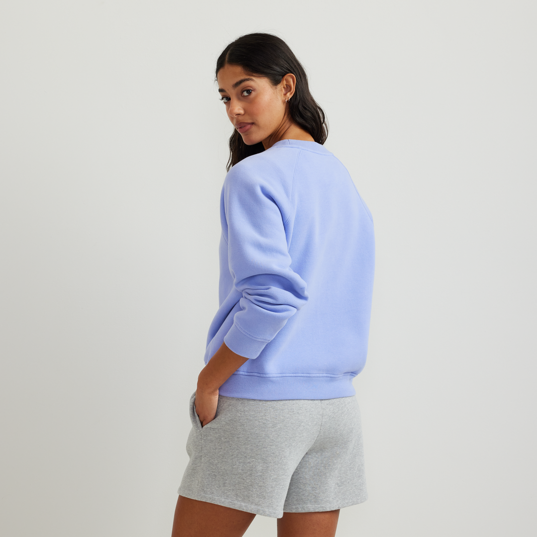 Dame iført ensfarvet sweatshirt med rund hals, lange ærmer og ribkanter