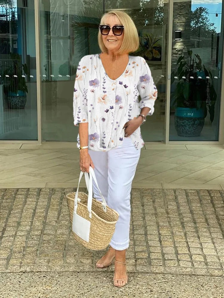 Dame iført blomstret bluse med V-hals og 3/4-ærmer