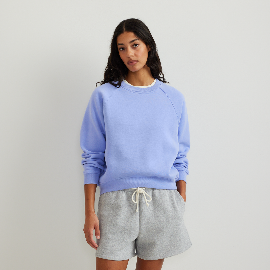 Dame iført ensfarvet sweatshirt med rund hals, lange ærmer og ribkanter