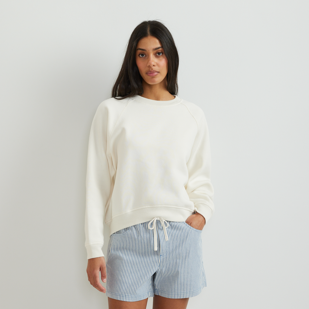 Dame iført ensfarvet sweatshirt med rund hals, lange ærmer og ribkanter