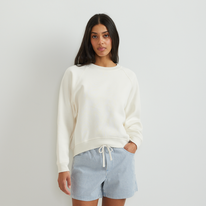 Dame iført ensfarvet sweatshirt med rund hals, lange ærmer og ribkanter