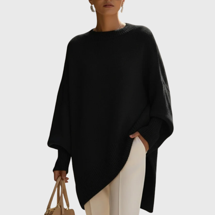 Dame iført ensfarvet oversize ponchobluse med rund hals og lange ribærmer