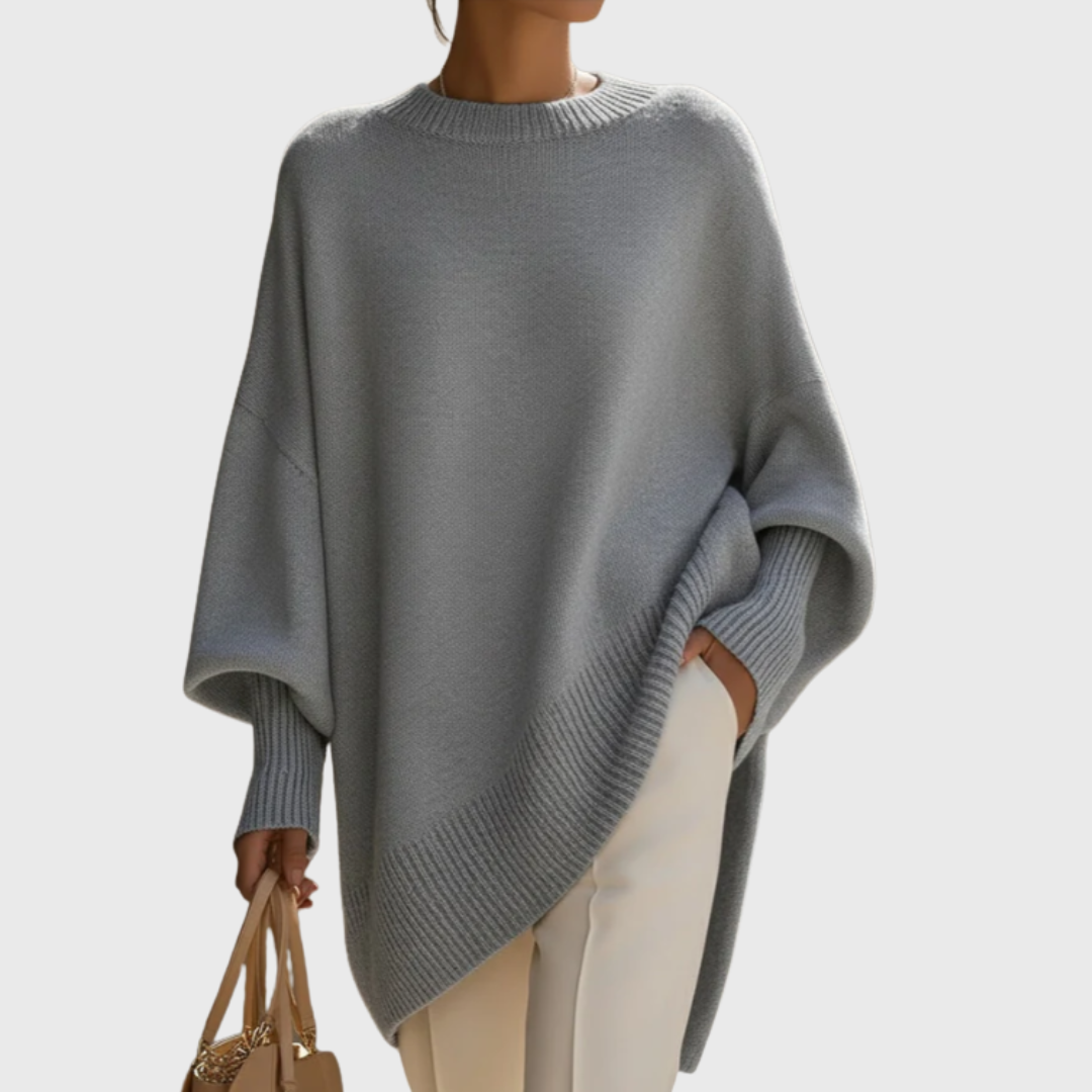 Dame iført ensfarvet oversize ponchobluse med rund hals og lange ribærmer