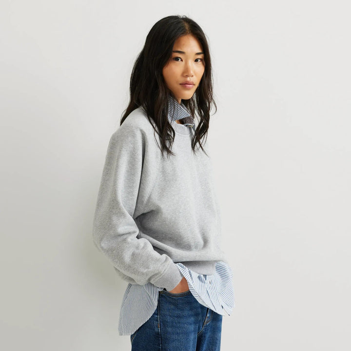 Dame iført ensfarvet sweatshirt med rund hals, lange ærmer og ribkanter