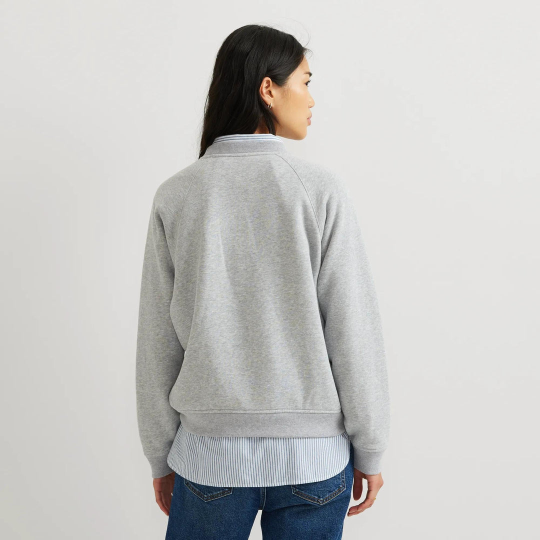Dame iført ensfarvet sweatshirt med rund hals, lange ærmer og ribkanter