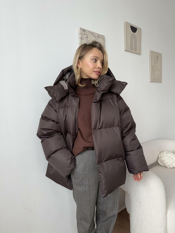 Dame i quiltet vinterjakke med hætte og oversize pasform
