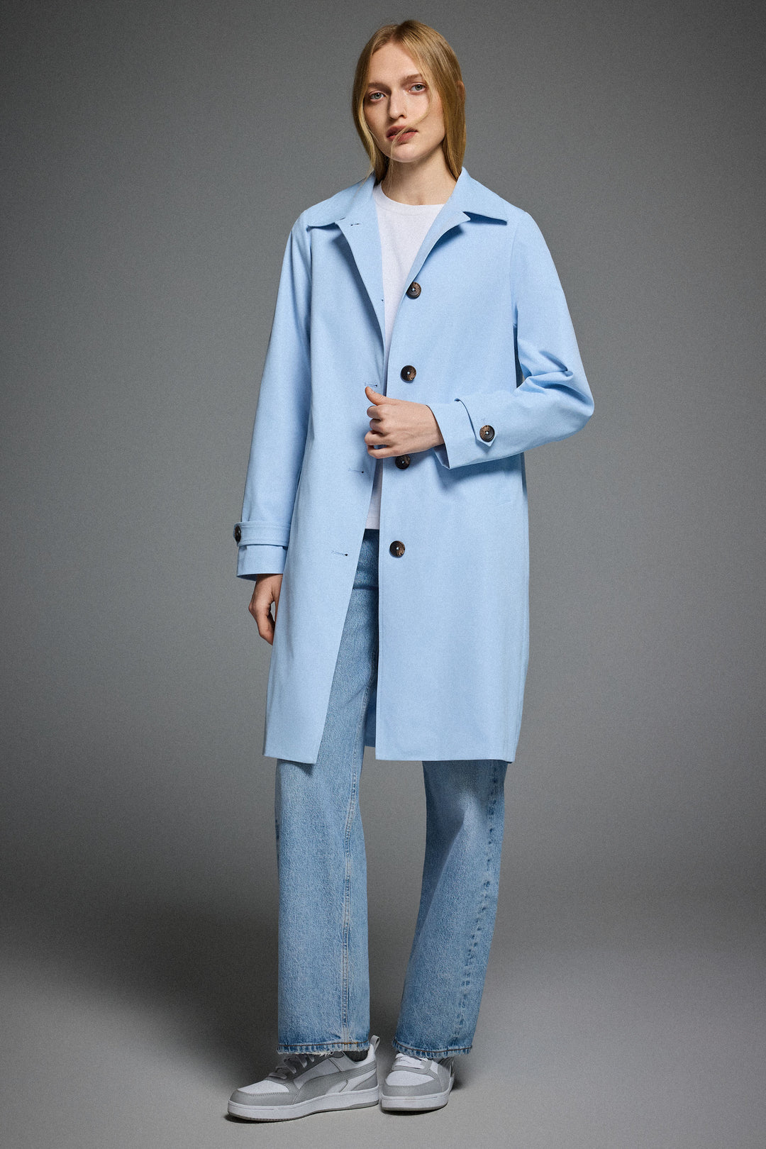 Dame i enradet trenchcoat med klassisk krave, knaplukning og lange ærmer