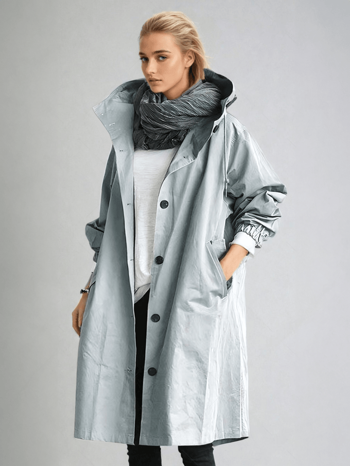 Dame i lang trenchcoat med hætte, knaplukning og frontlommer