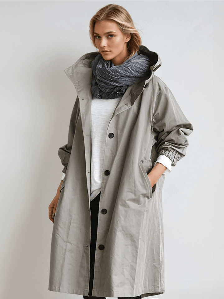 Dame i lang trenchcoat med hætte, knaplukning og frontlommer