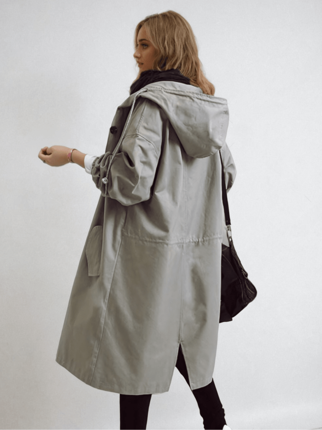Dame i lang trenchcoat med hætte, knaplukning og frontlommer