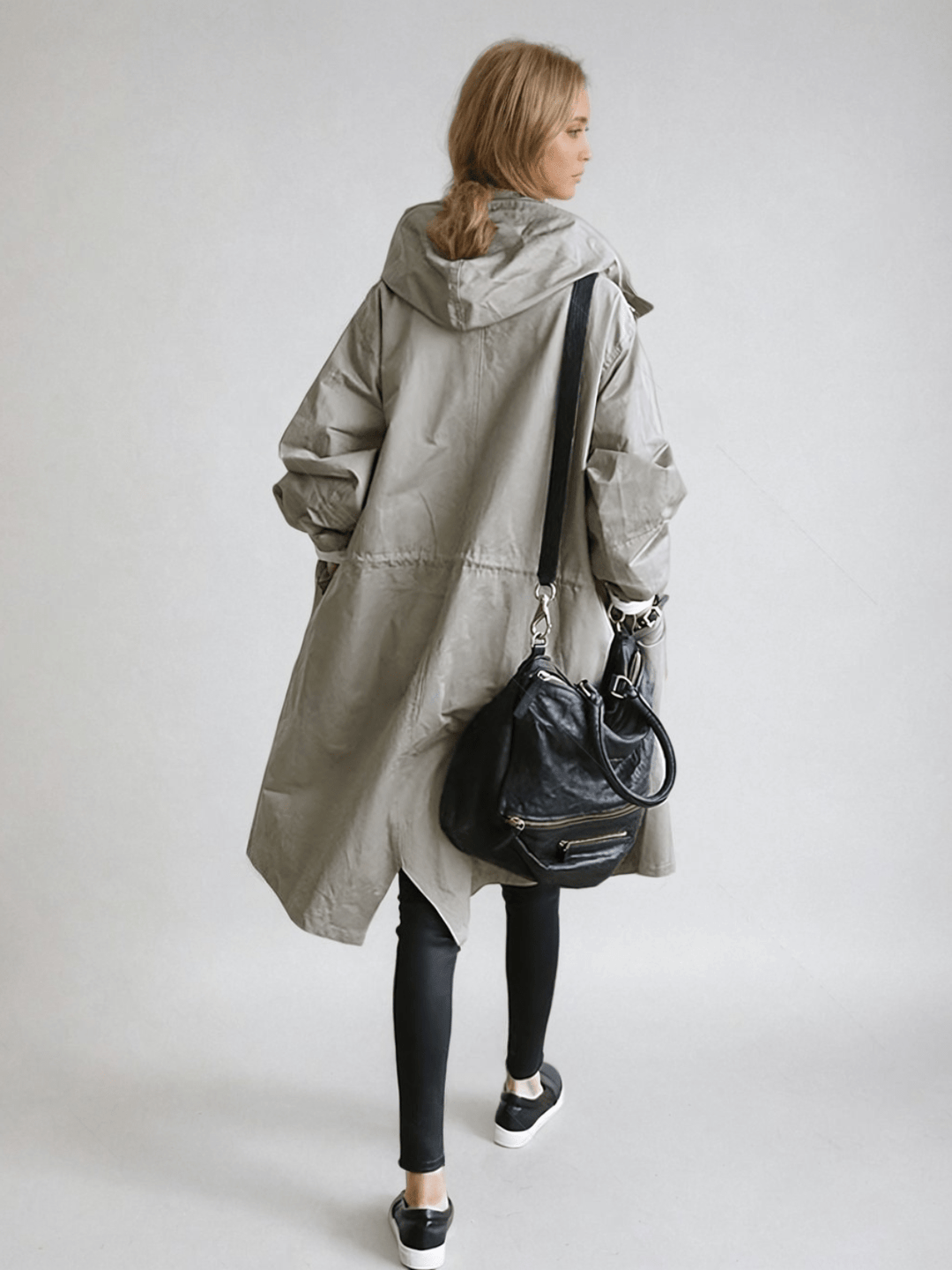 Dame i lang trenchcoat med hætte, knaplukning og frontlommer