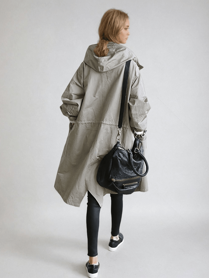 Dame i lang trenchcoat med hætte, knaplukning og frontlommer