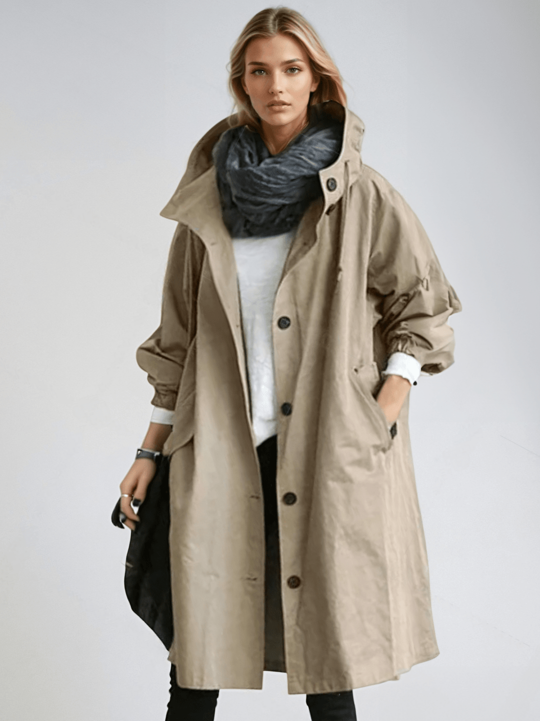 Dame i lang trenchcoat med hætte, knaplukning og frontlommer