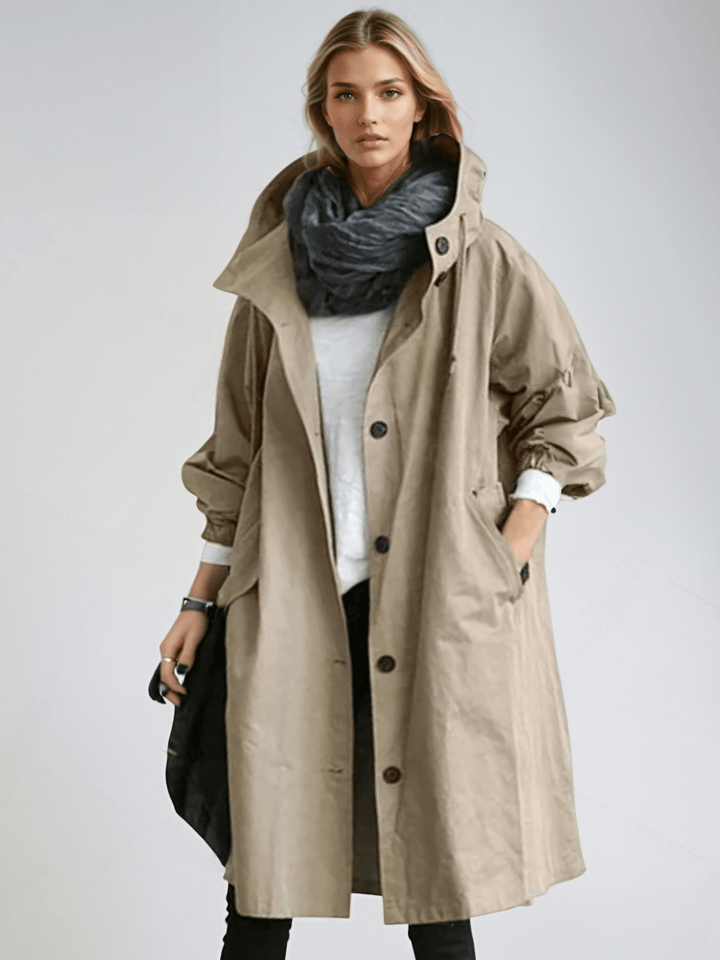 Dame i lang trenchcoat med hætte, knaplukning og frontlommer