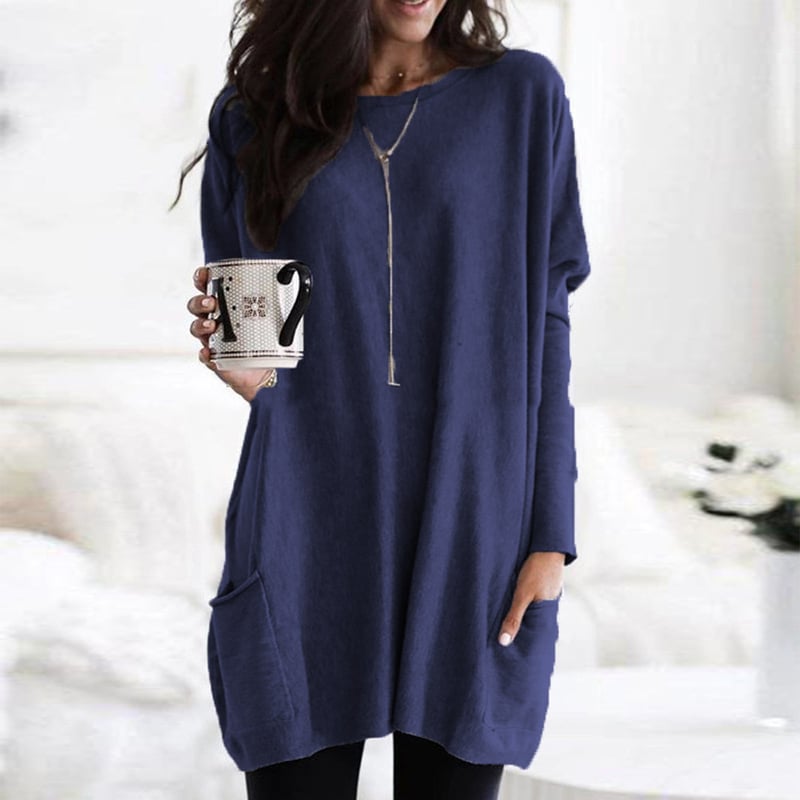 Dame i ensfarvet oversized sweaterkjole med rund hals, lange ærmer og forlommer