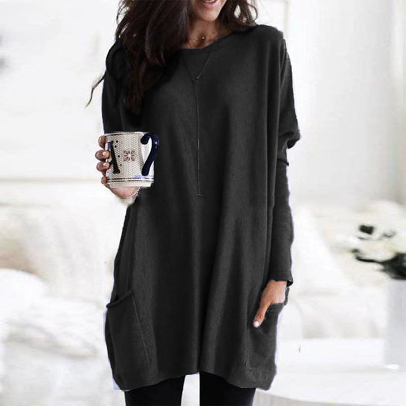 Dame i ensfarvet oversized sweaterkjole med rund hals, lange ærmer og forlommer