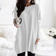 Dame i ensfarvet oversized sweaterkjole med rund hals, lange ærmer og forlommer
