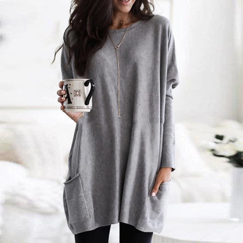 Dame i ensfarvet oversized sweaterkjole med rund hals, lange ærmer og forlommer